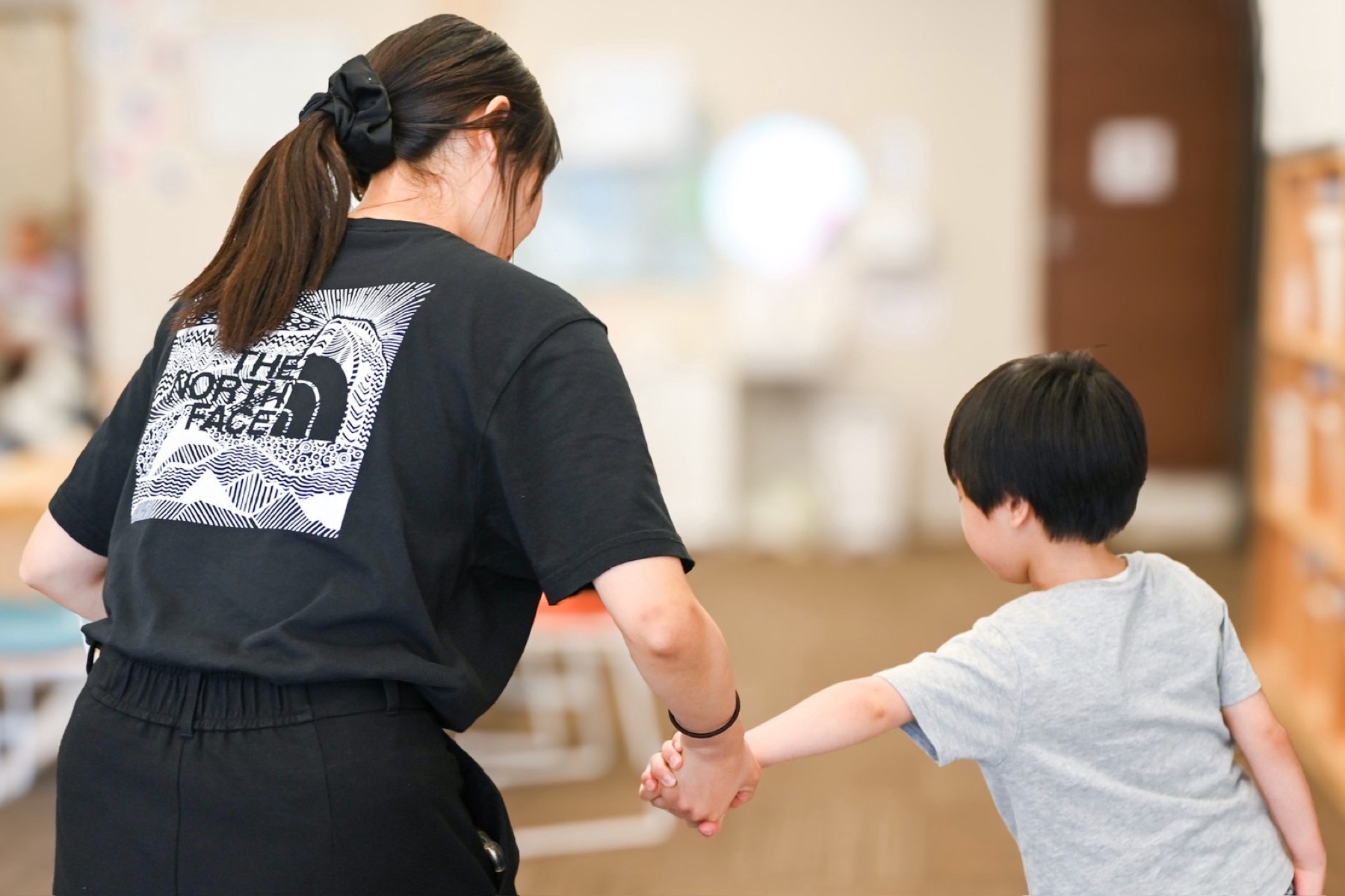 子どもと手をつないで歩くスタッフ
